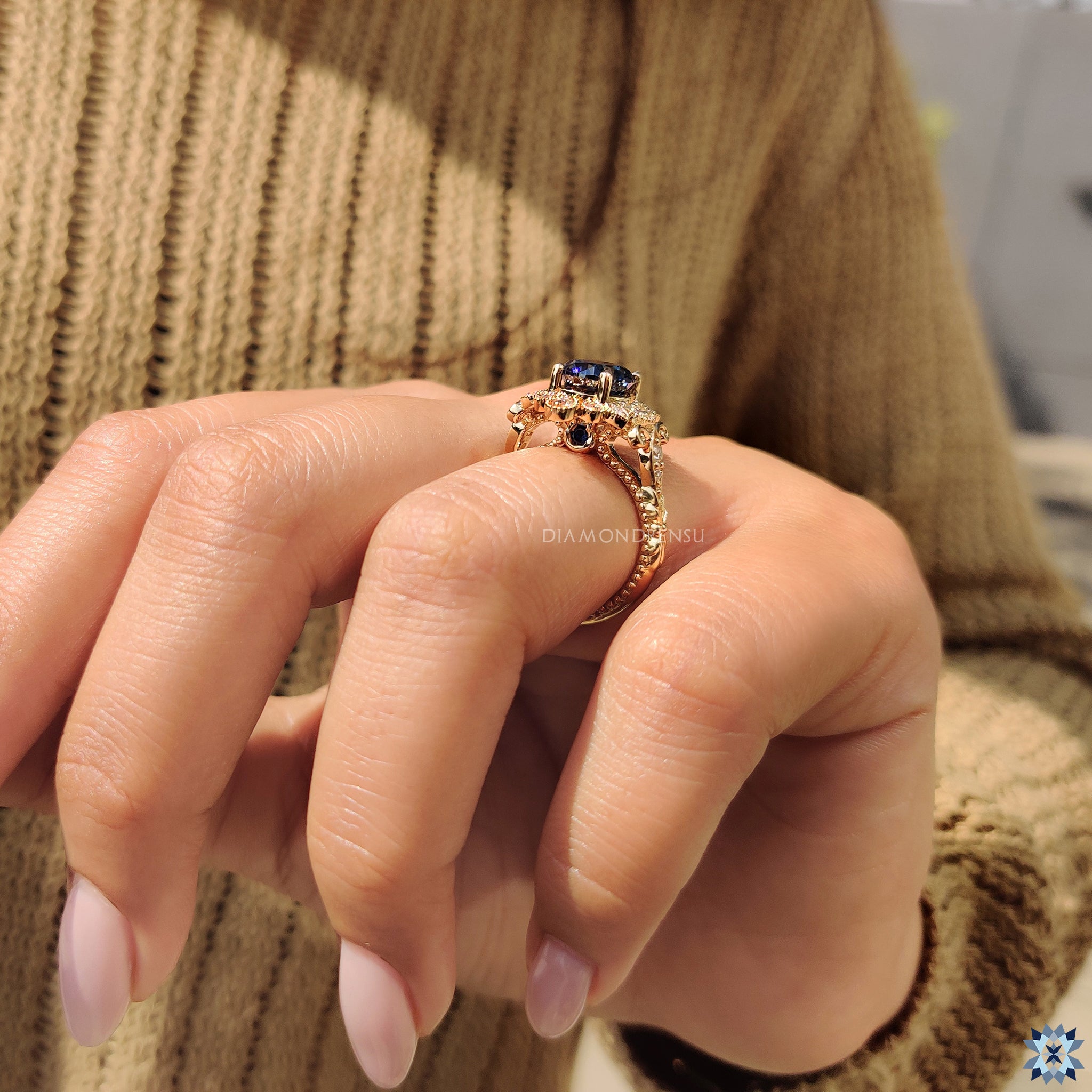 Vintage engagement ring with halo setting and blue round moissanite.
