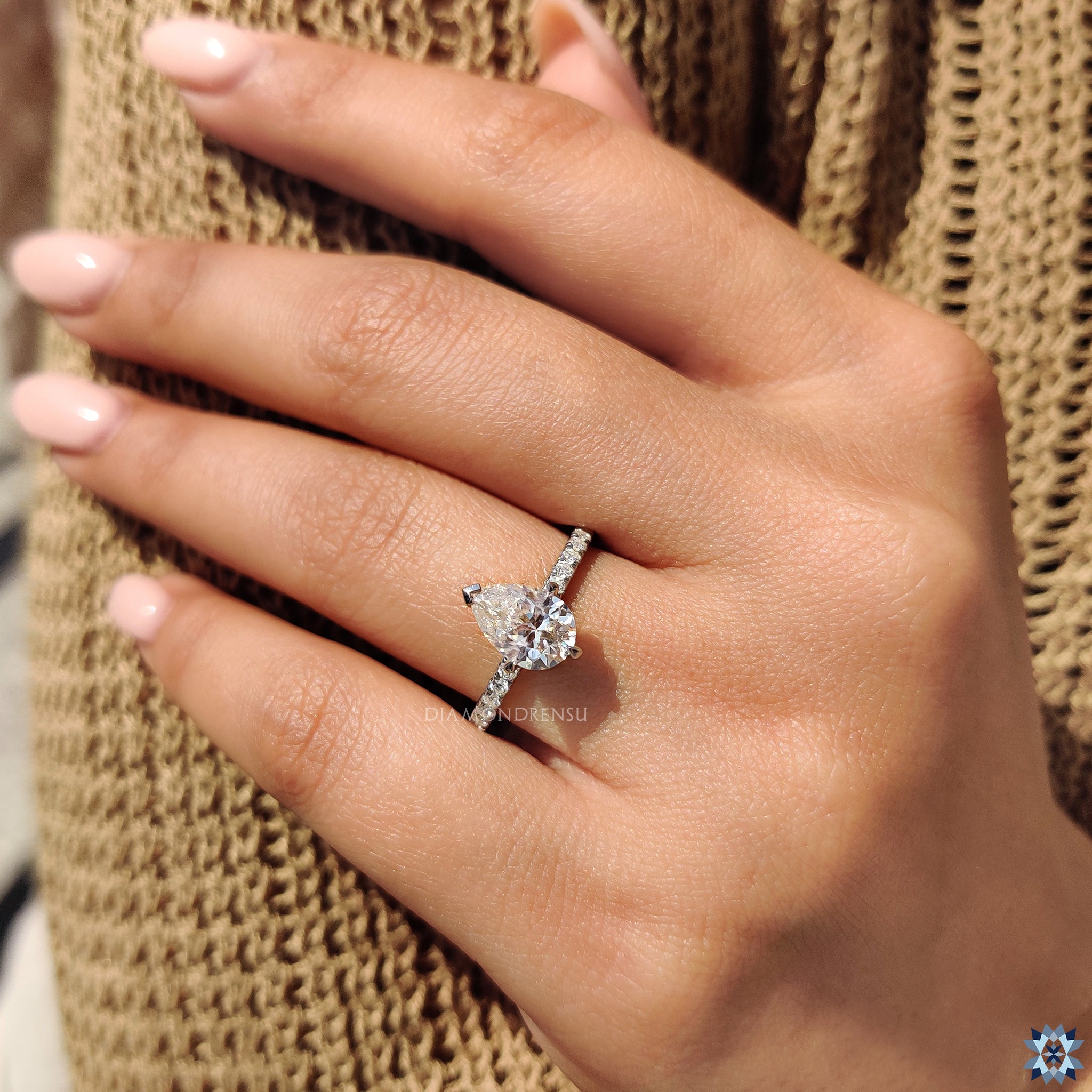 Handmade ring with white gold, pear moissanite, and round pave band.
