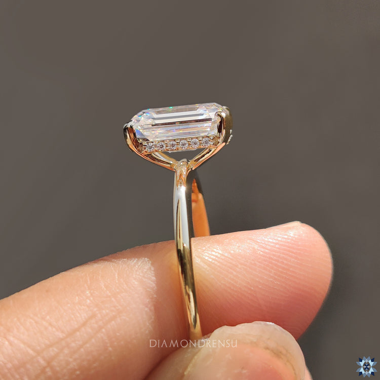 Handmade ring in yellow gold featuring an emerald cut moissanite centre.

