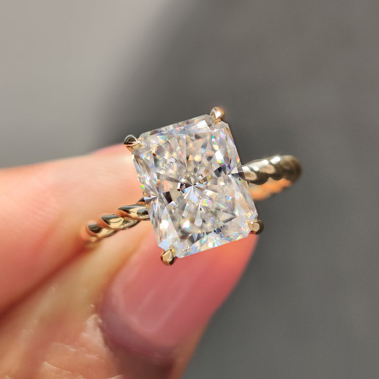 Radiant cut moissanite engagement ring with round cut hidden halo detail.

