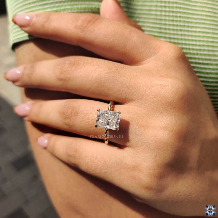 UK engagement ring showcasing radiant cut and hidden halo round accents.
