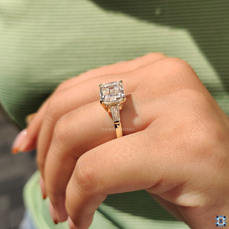 UK engagement ring with emerald cut stone and two side baguettes.
