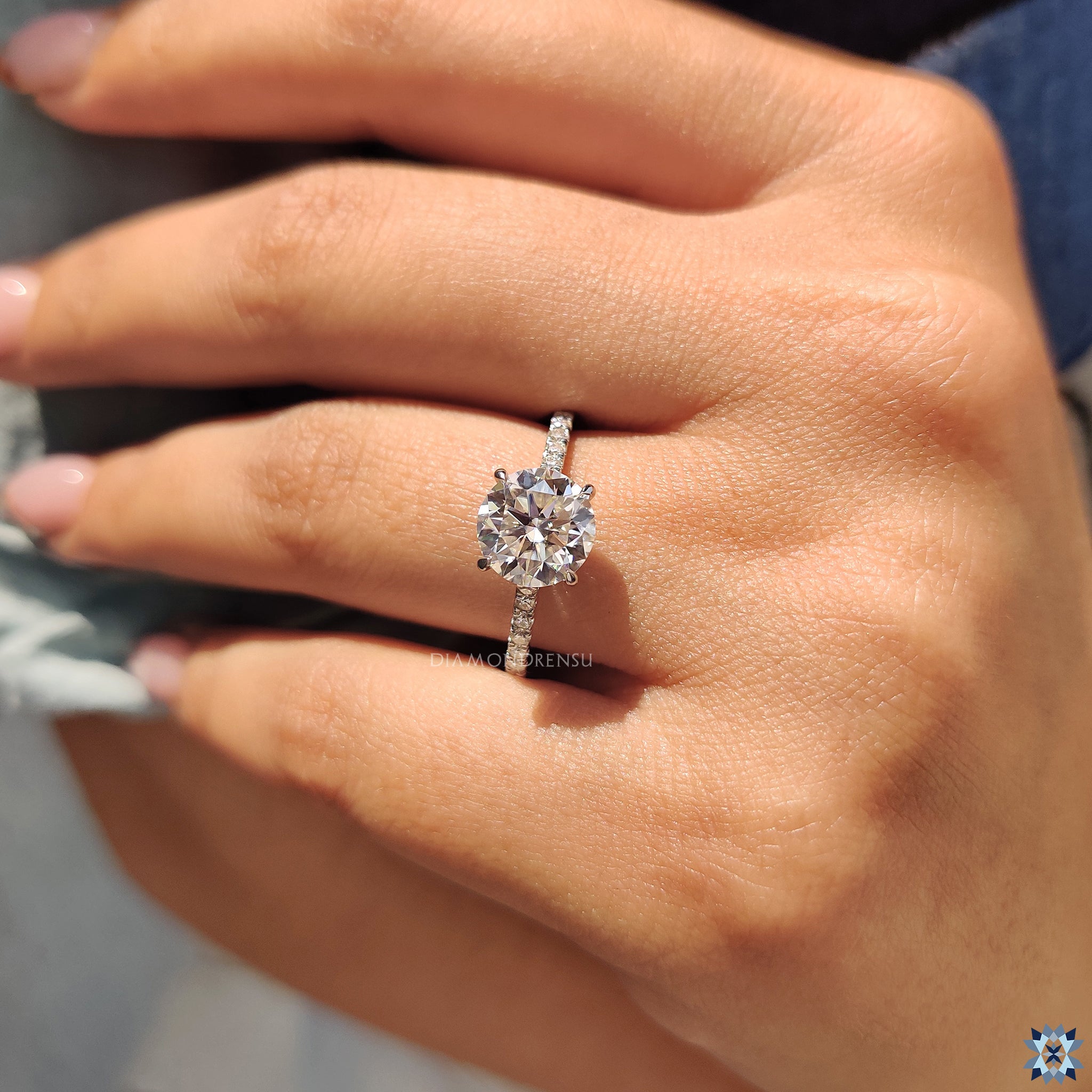 Pave band enhances round cut moissanite in elegant setting.
