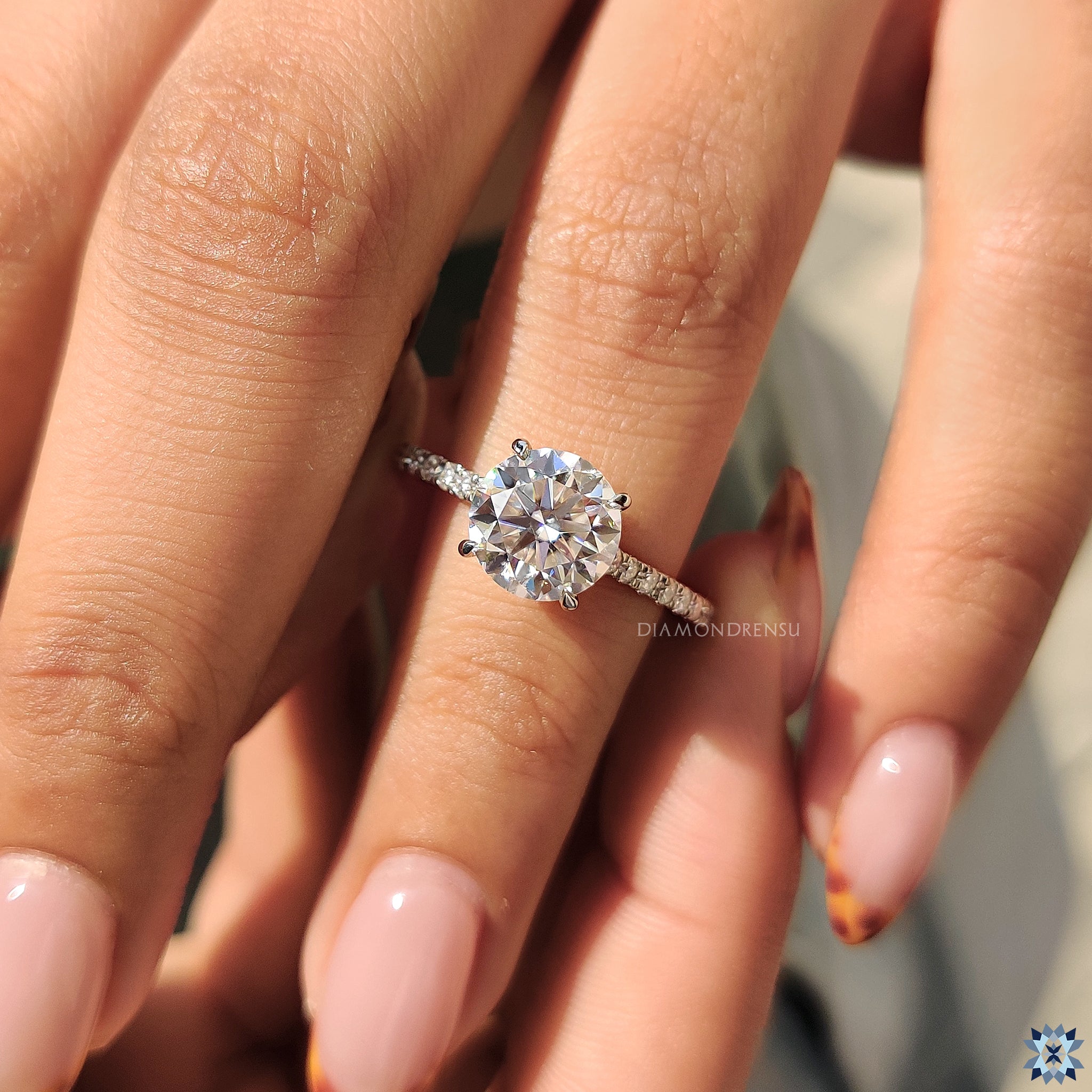 4 claw prong ring showcasing round moissanite and pave details.
