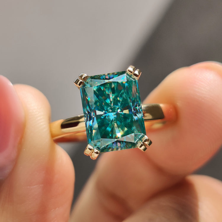 Radiant cut moissanite ring with vibrant cyan blue gemstone centre.
