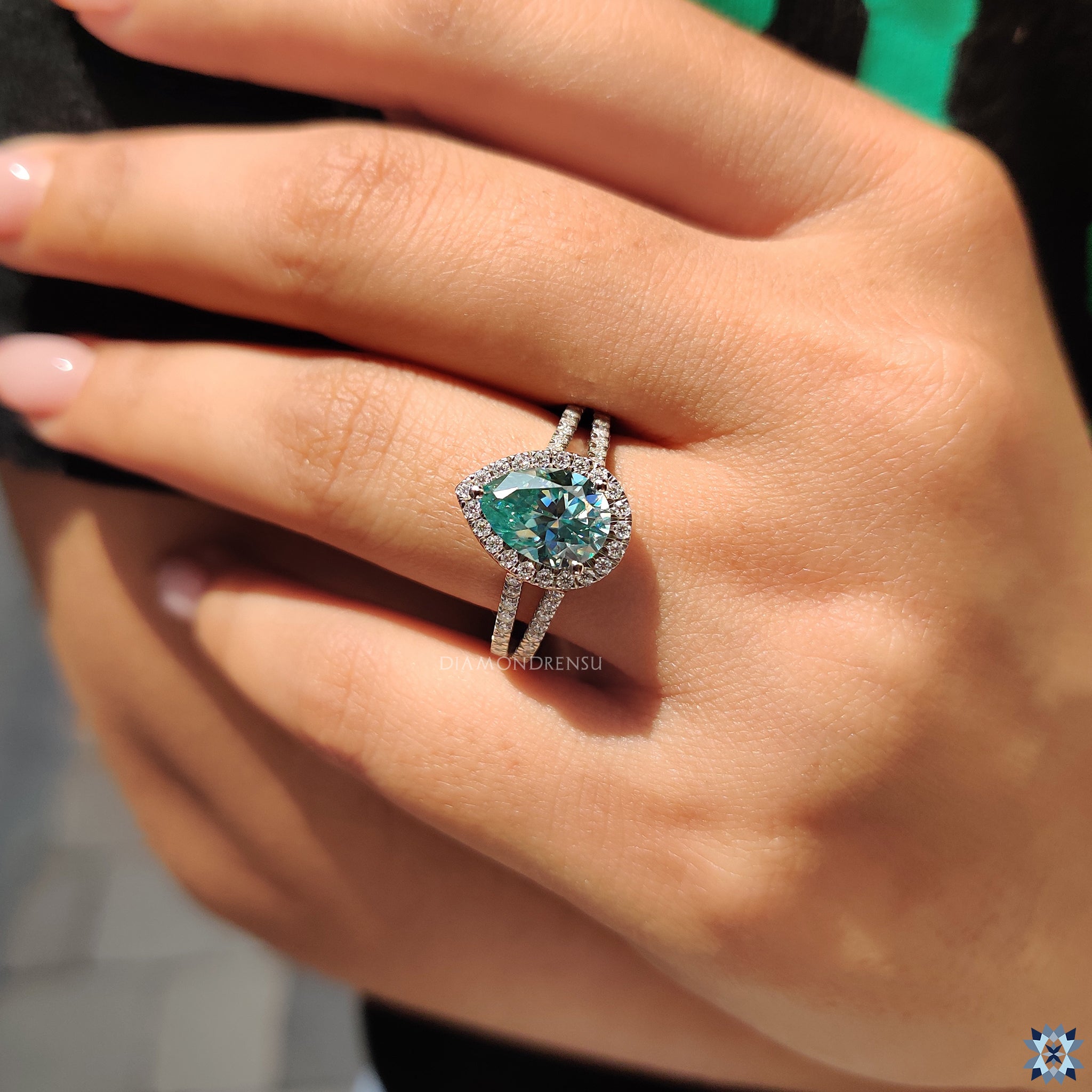 Round cut halo setting highlights the vibrant cyan blue moissanite.
