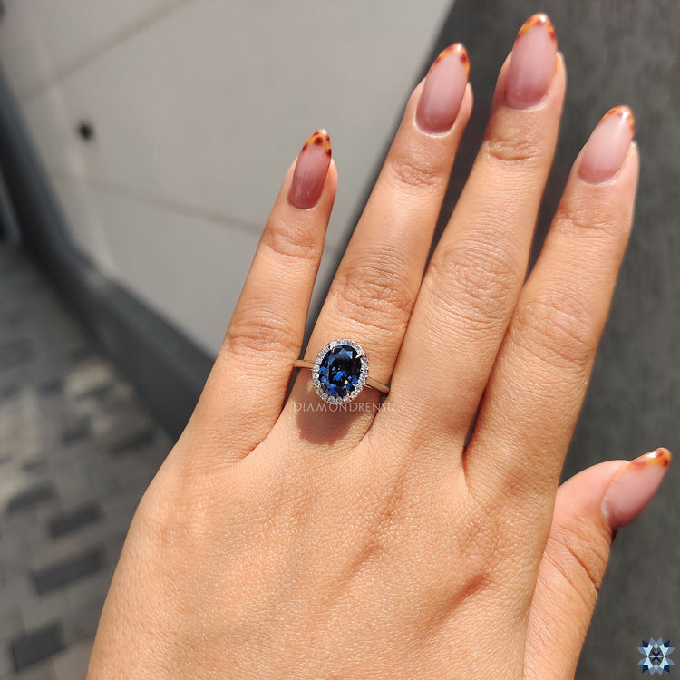 Handmade oval cut moissanite ring with halo design in white gold cathedral setting.
