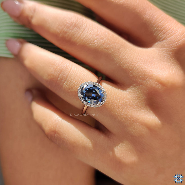 Handmade jewelry with oval cut blue moissanite and detailed round cut halo band.
