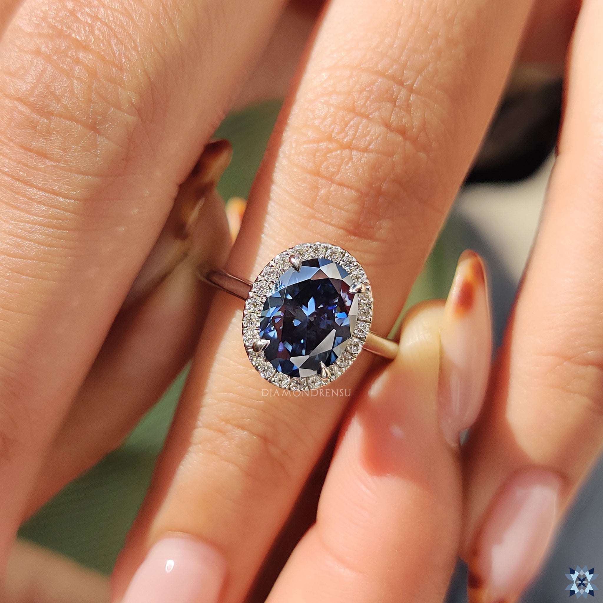 White gold oval engagement ring with cathedral shoulders and radiant halo setting.
