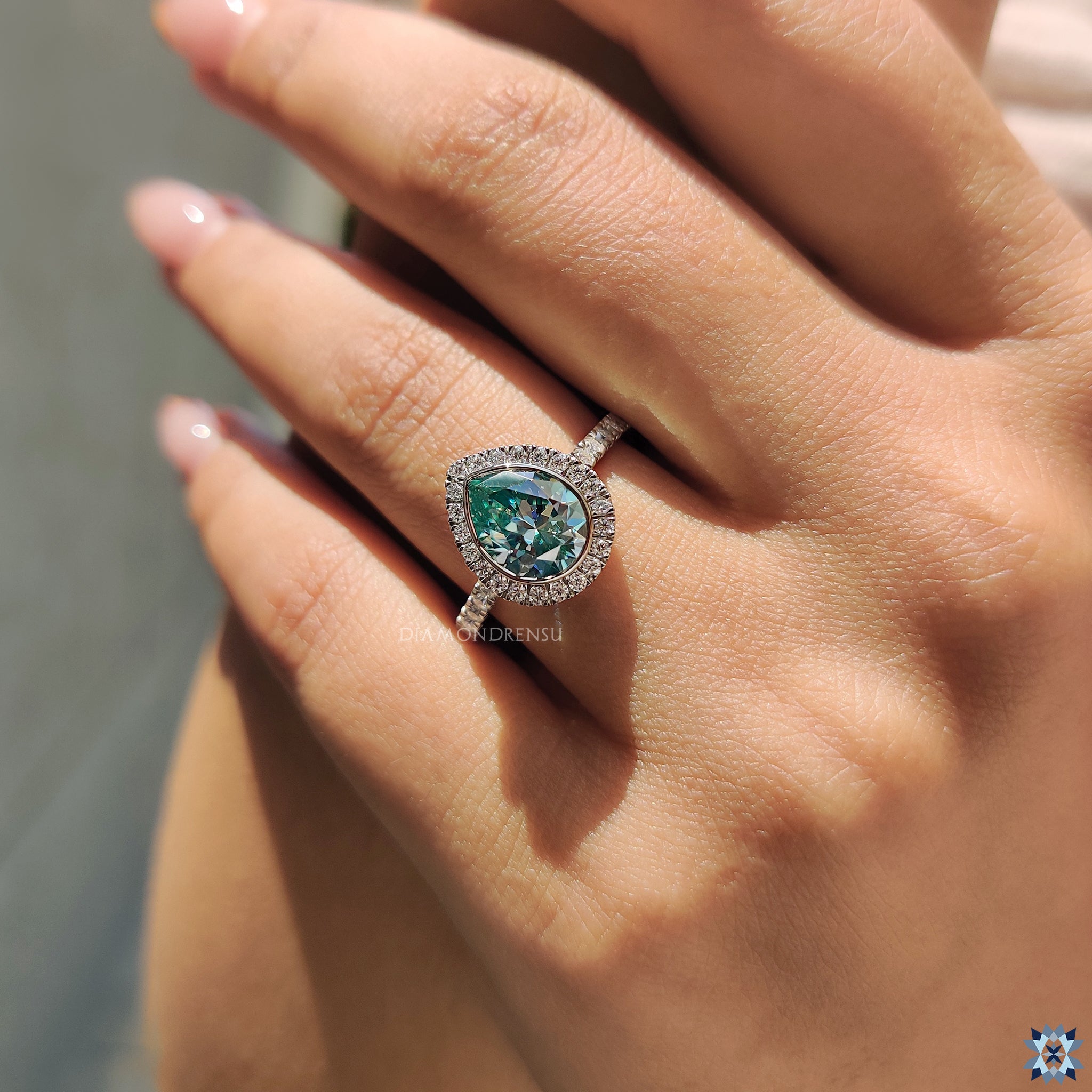 Round cut halo surrounding pear moissanite in a white gold engagement ring.
