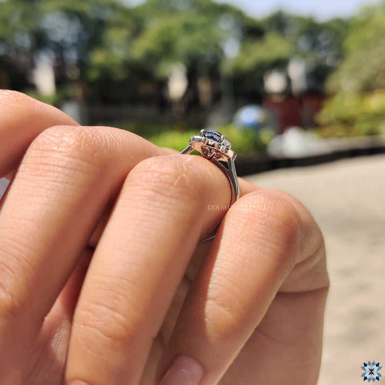 White gold engagement ring with oval dark blue Moissanite and milgrain design.
