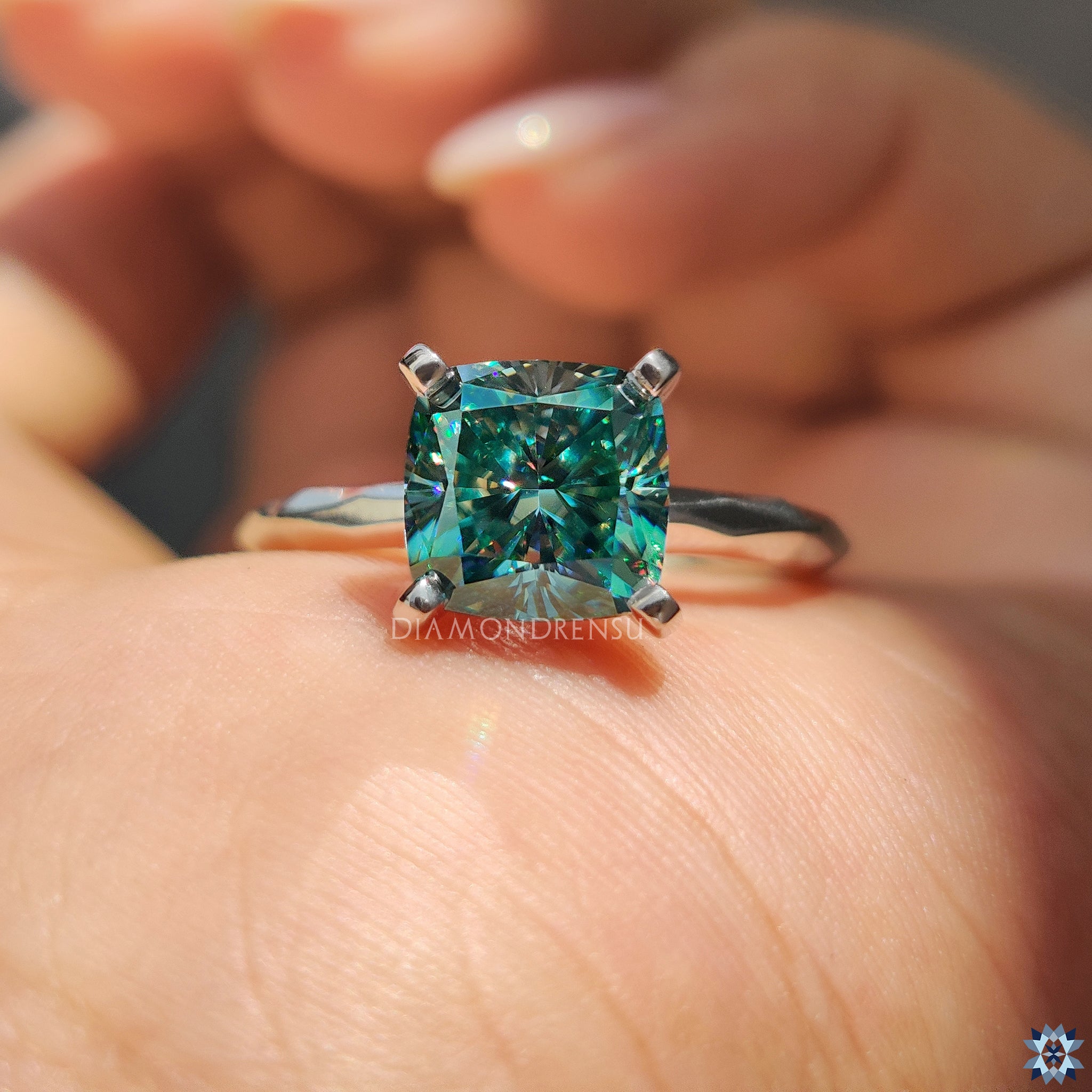 Solitaire engagement ring with cyan blue moissanite and artisan hammer finish.
