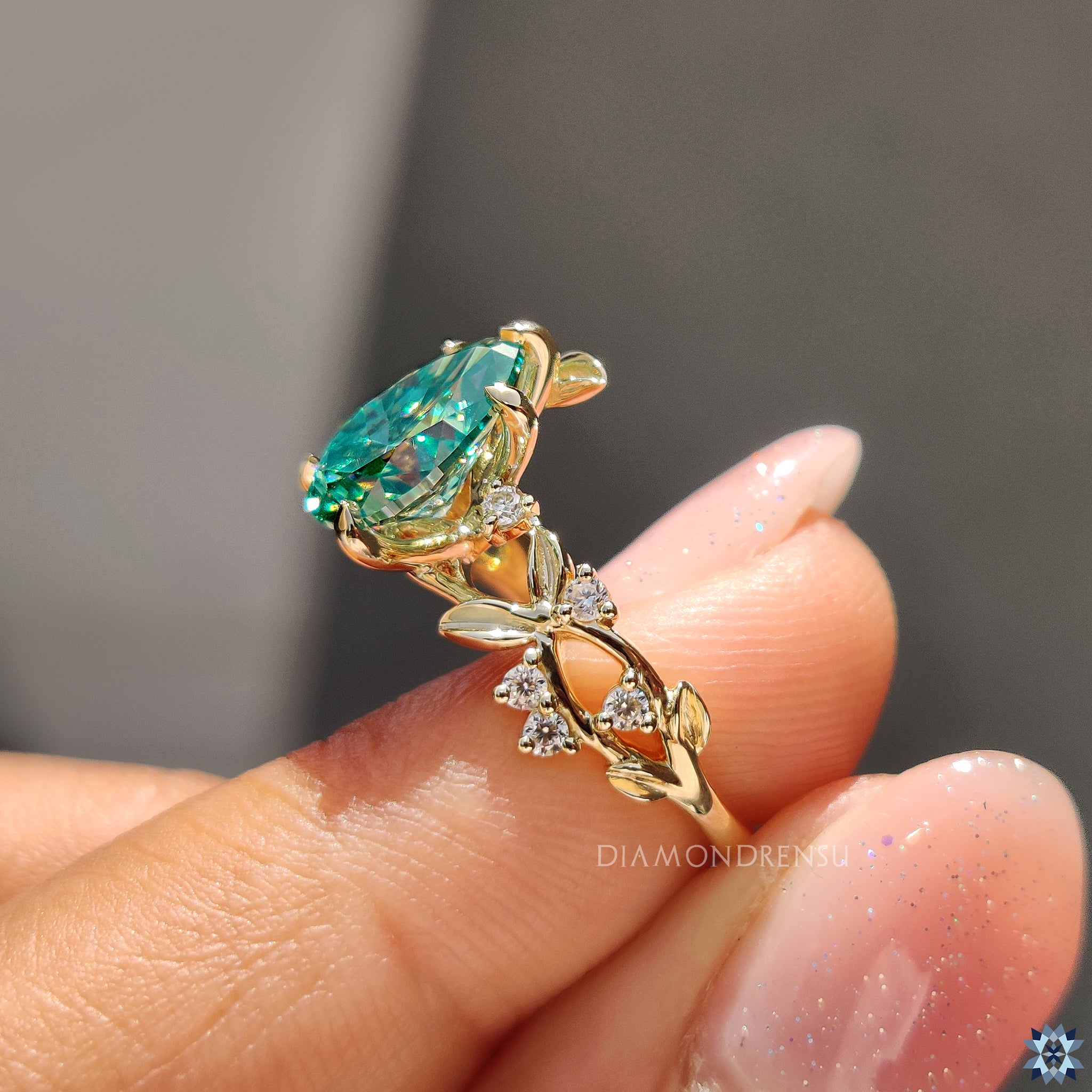 UK engagement ring with pear shaped green moissanite and organic nature-inspired setting.
