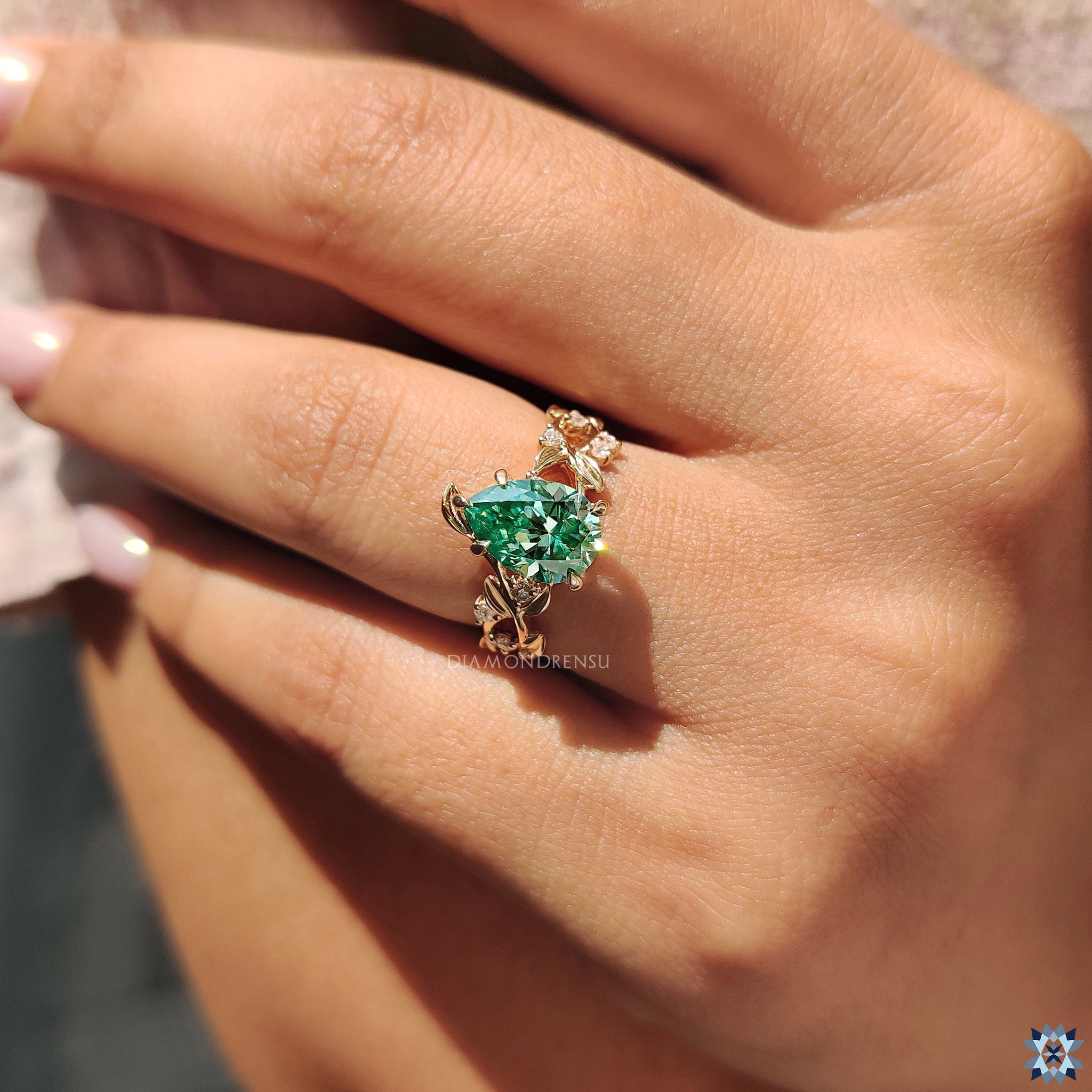 Green pear cut moissanite ring with 5 claw prong and custom nature motif setting.
