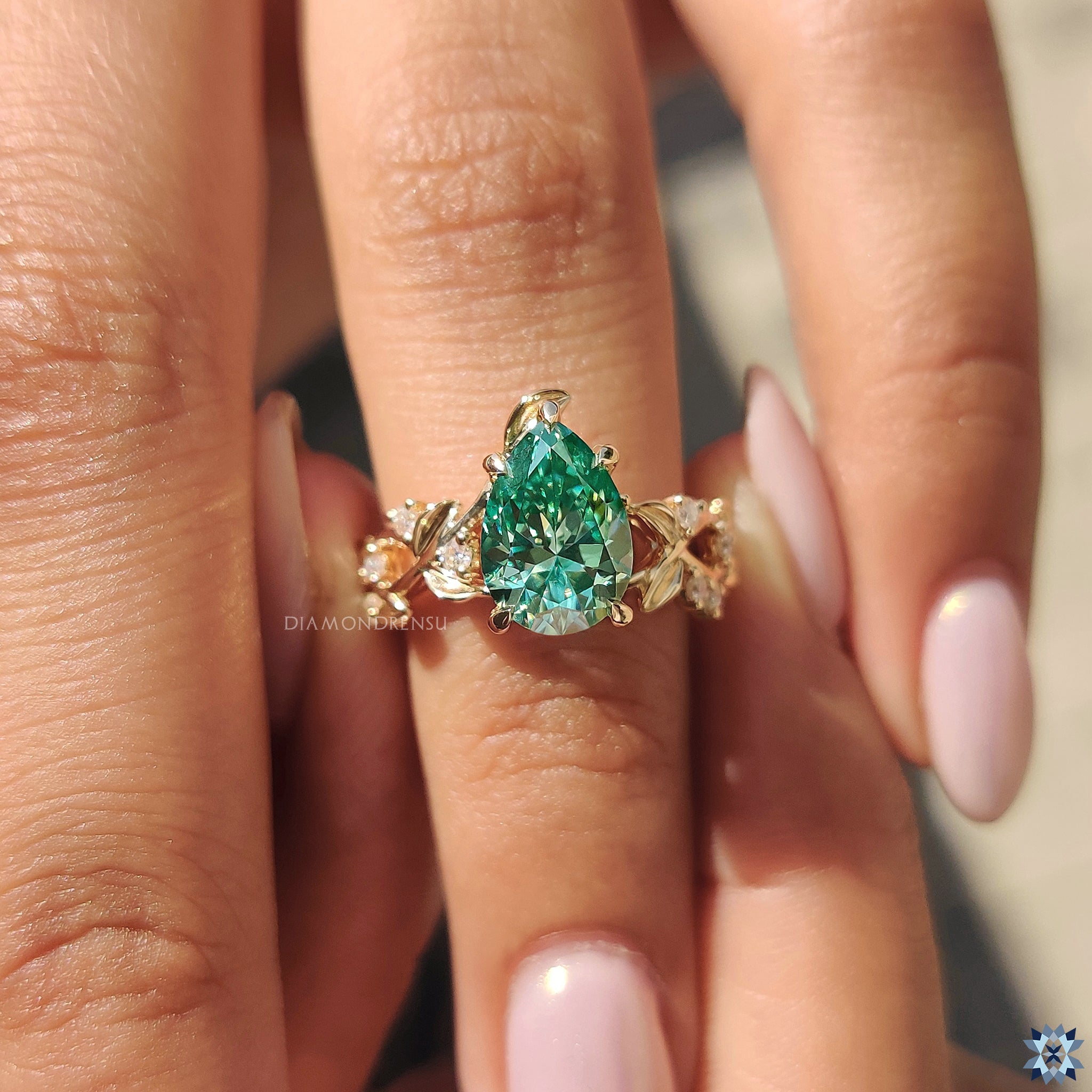 Yellow gold pear moissanite ring with elegant round side stones and handmade detailing.
