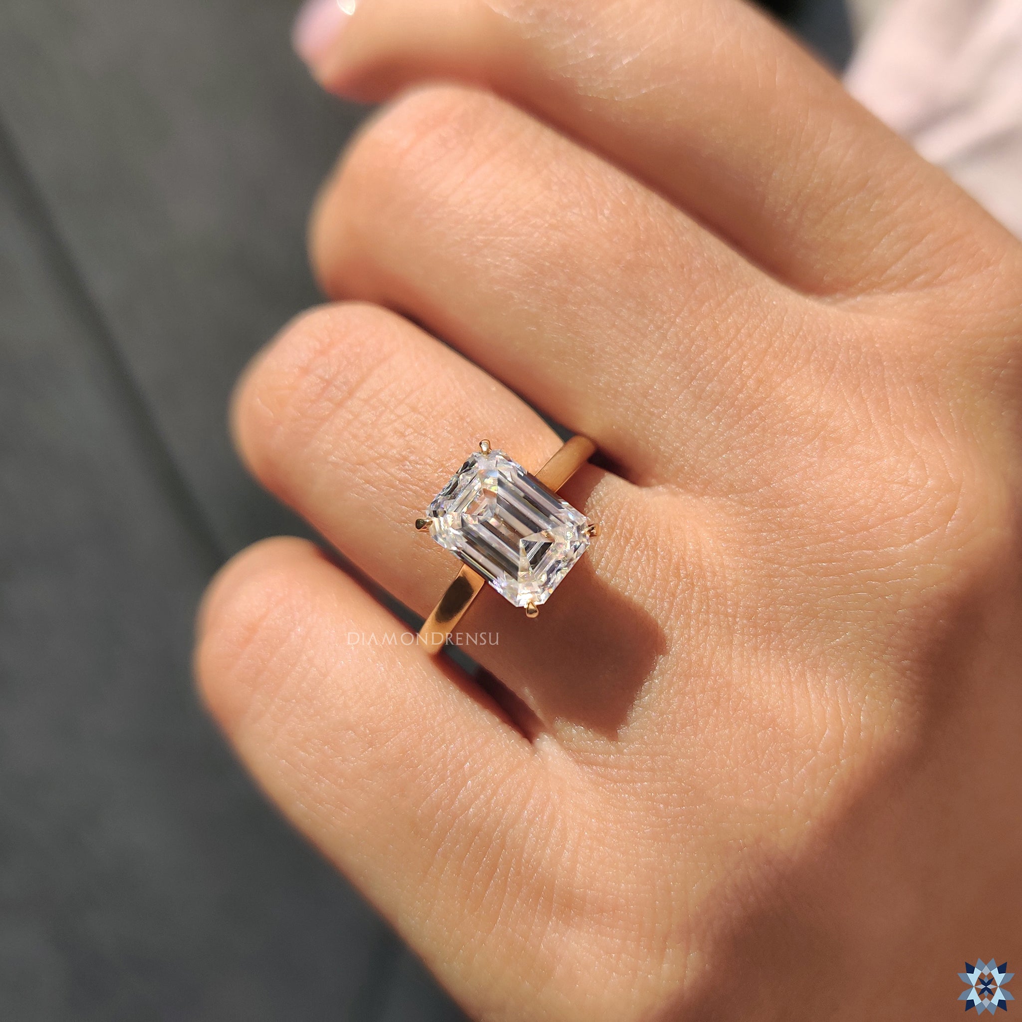 Classic engagement ring with emerald cut moissanite in a 4 claw yellow gold setting.
