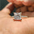 Moissanite gold ring with princess cut stone and round cut pave band in yellow gold.
