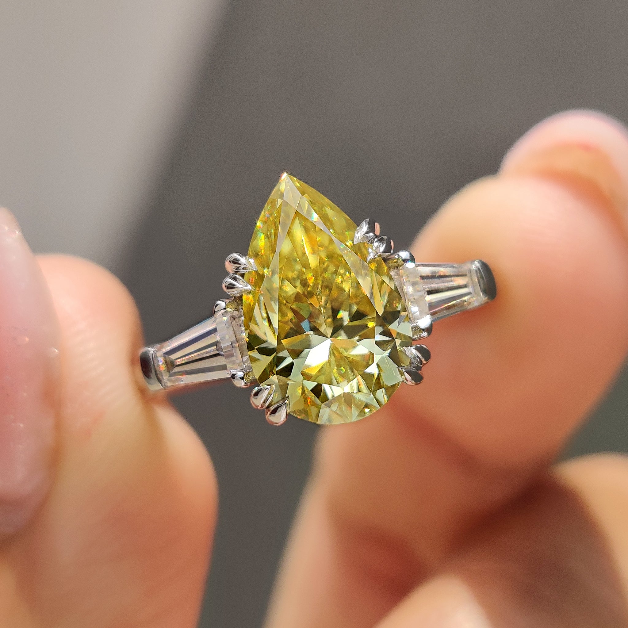 Canary yellow pear cut Moissanite ring with tapered baguette side stones in white gold setting.
