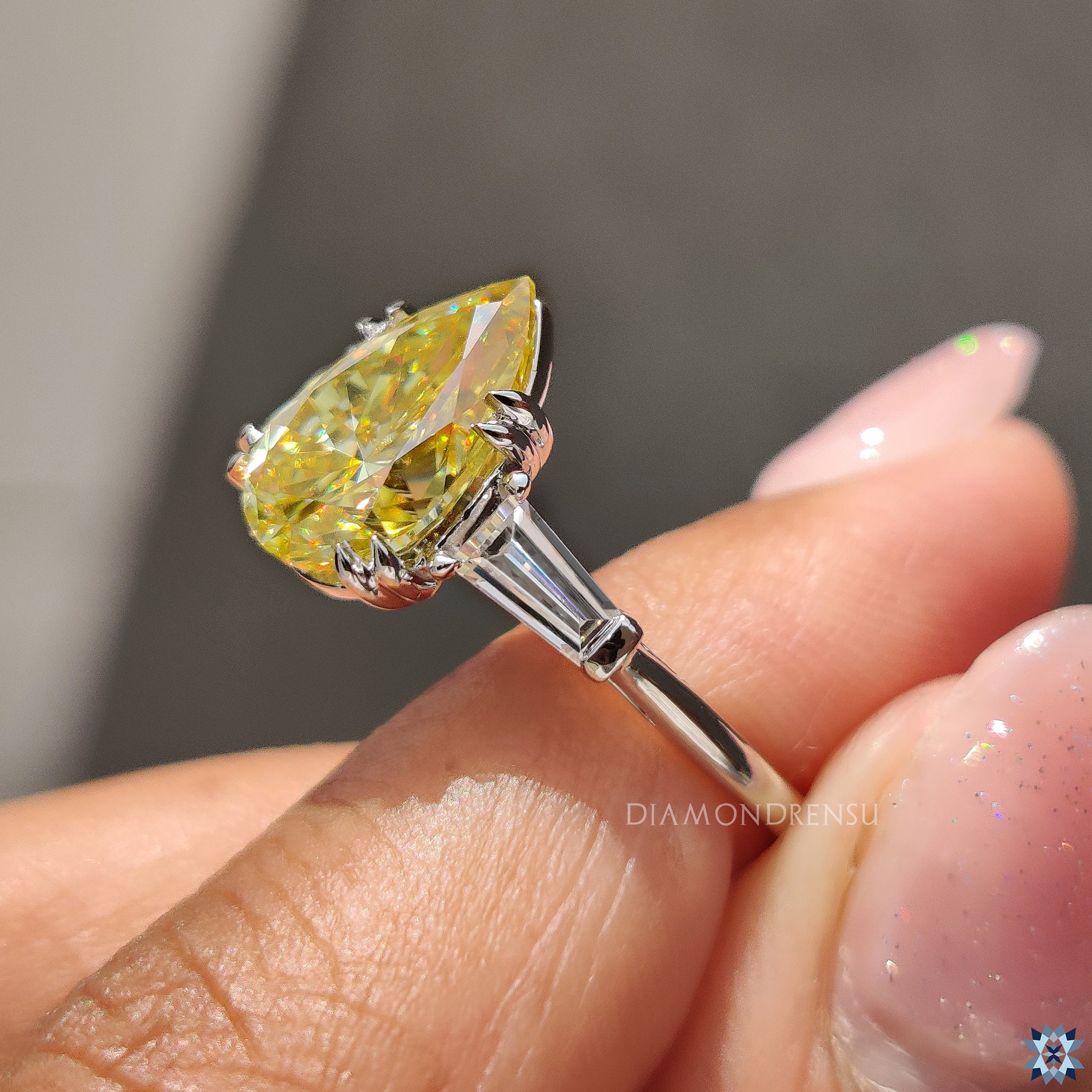 Handmade pear cut Moissanite ring in bright canary yellow with tapered side stones.

