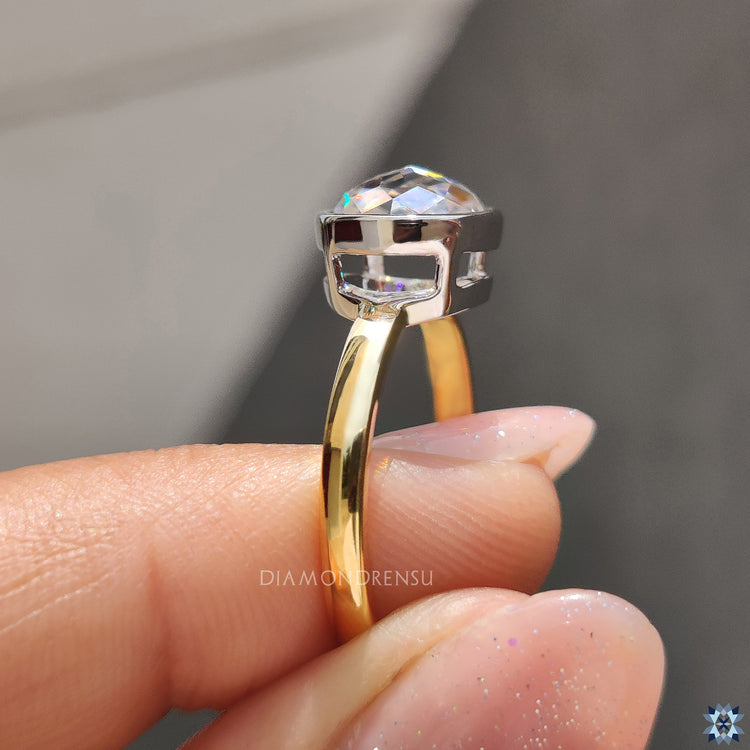 White and yellow gold Moissanite engagement ring with secure bezel setting.
