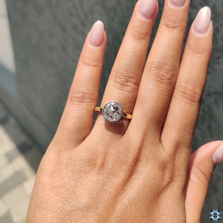 Simple bezel solitaire ring featuring round rose cut Moissanite for classic elegance.
