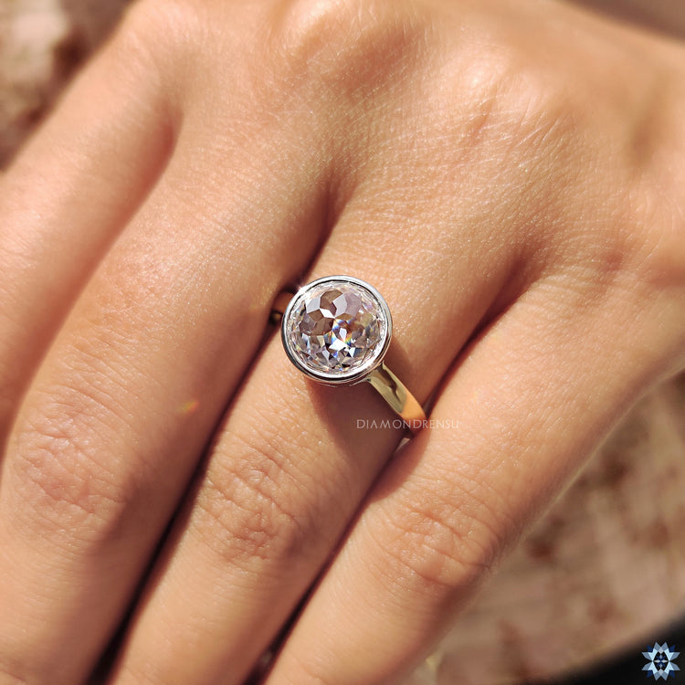 Round rose cut Moissanite solitaire ring with classic bezel setting in white and yellow gold.

