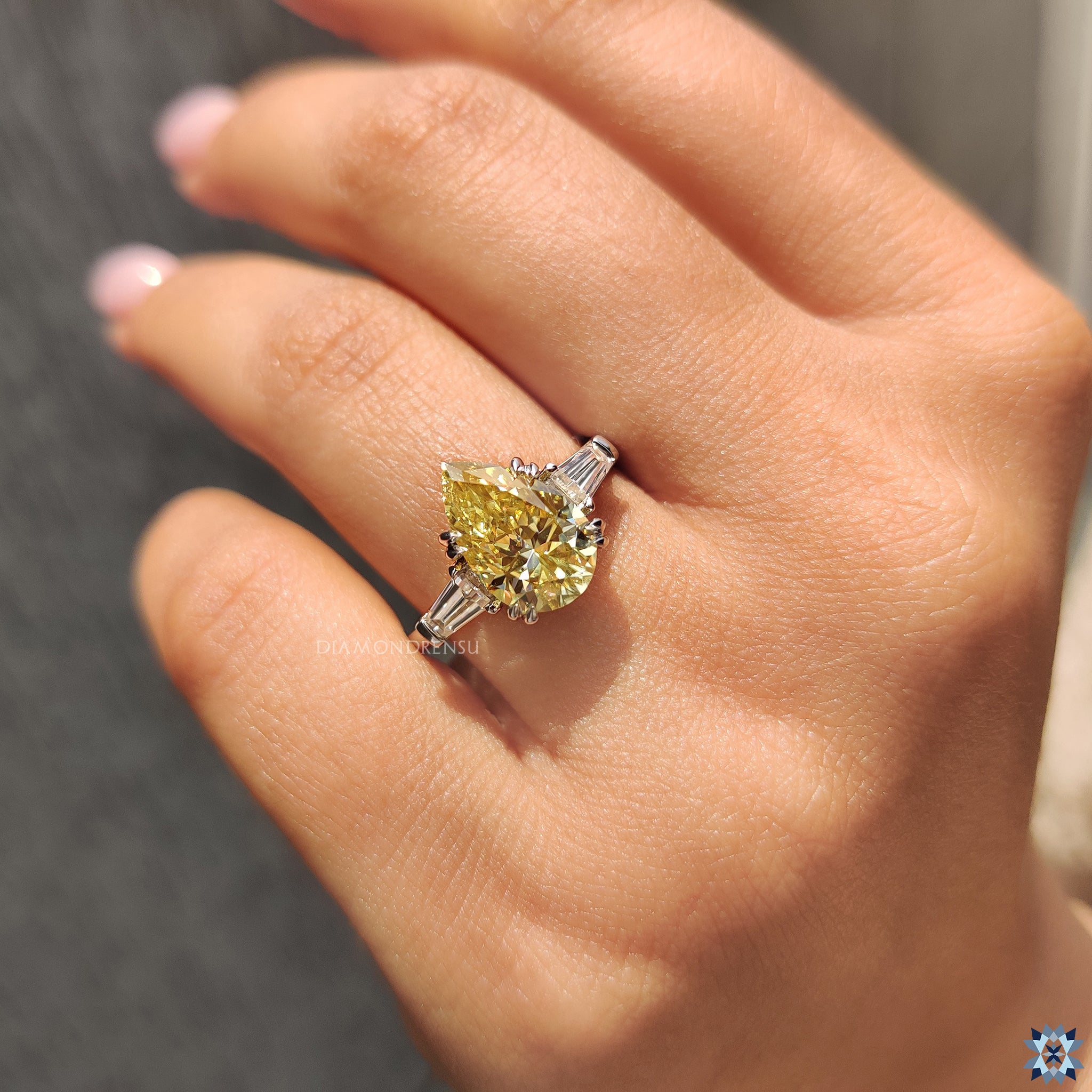 Moissanite for an engagement ring in canary yellow pear cut with baguette side stones.
