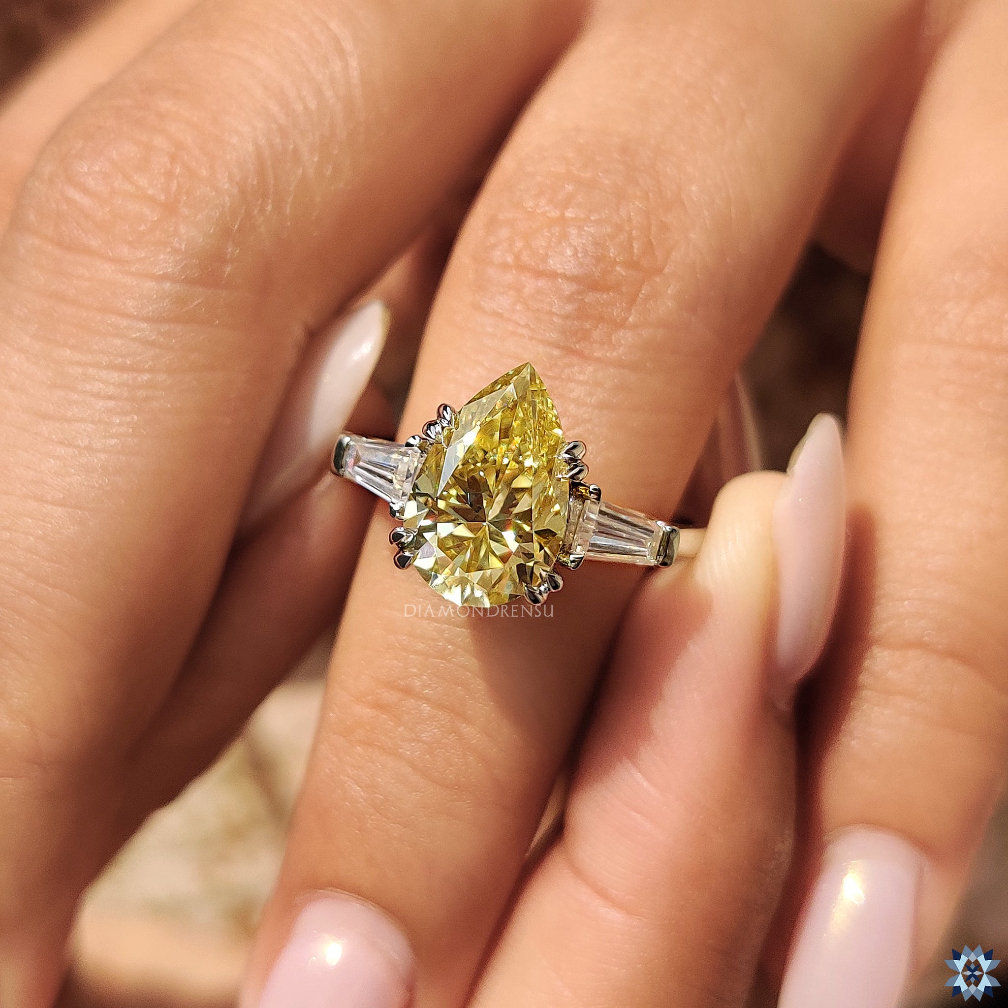 Three stone engagement ring with pear cut canary yellow Moissanite and double claw prongs.
