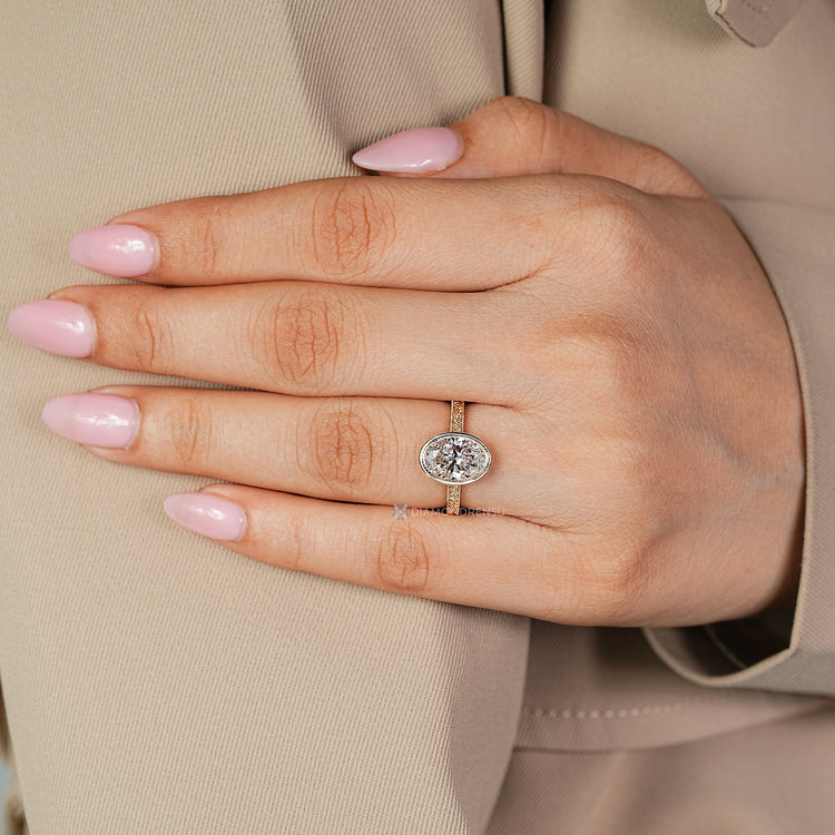 Oval solitaire diamond ring with filigree details.