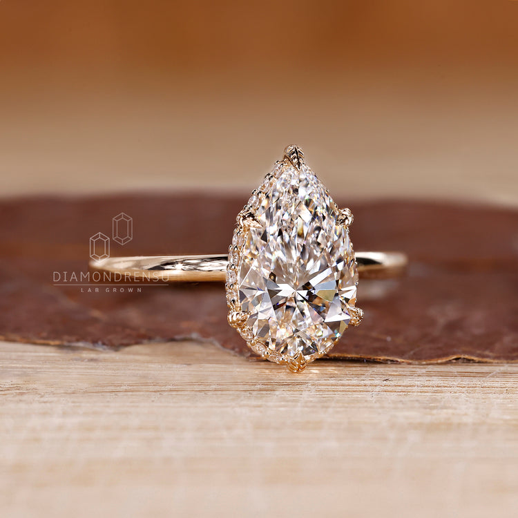 Pear diamond ring with round side halo and prongs.