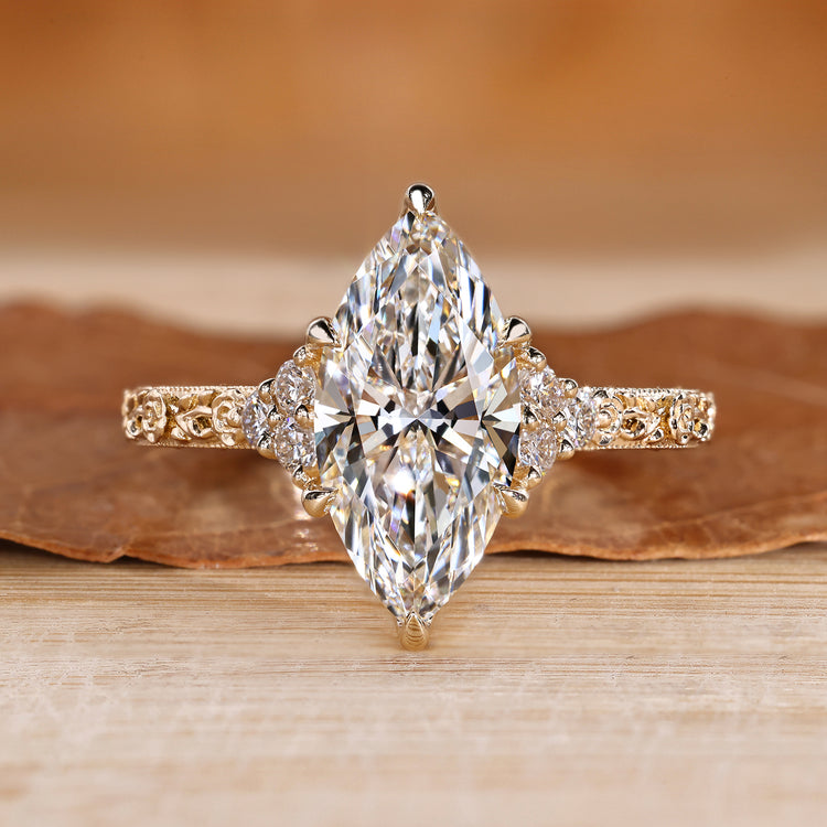 Marquise engagement ring with round side stone and muse setting.