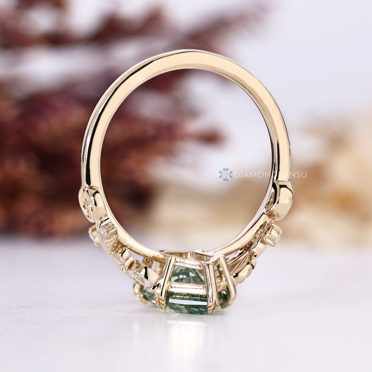 Green centre diamond ring with six leaf style prongs.