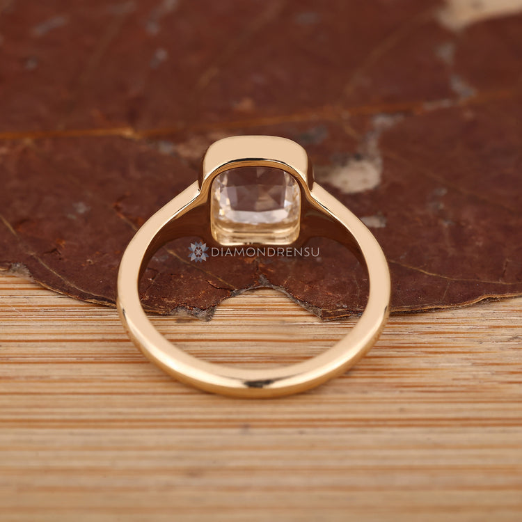 Bezel engagement ring with solitaire cushion diamond.