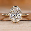 Oval diamond ring with bezel setting.