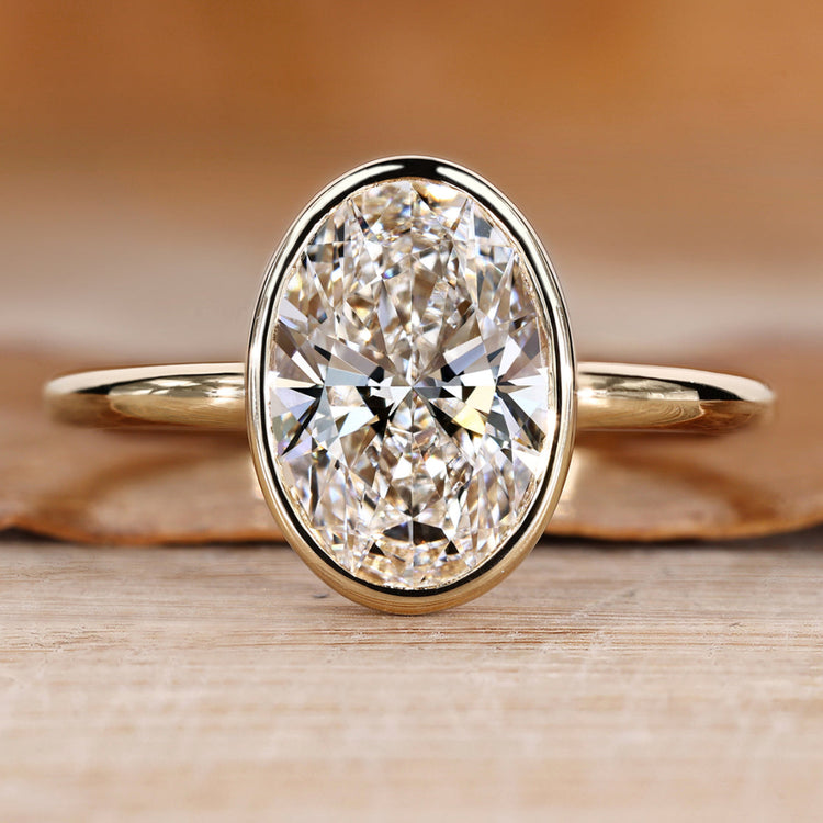 Oval diamond ring with bezel setting.