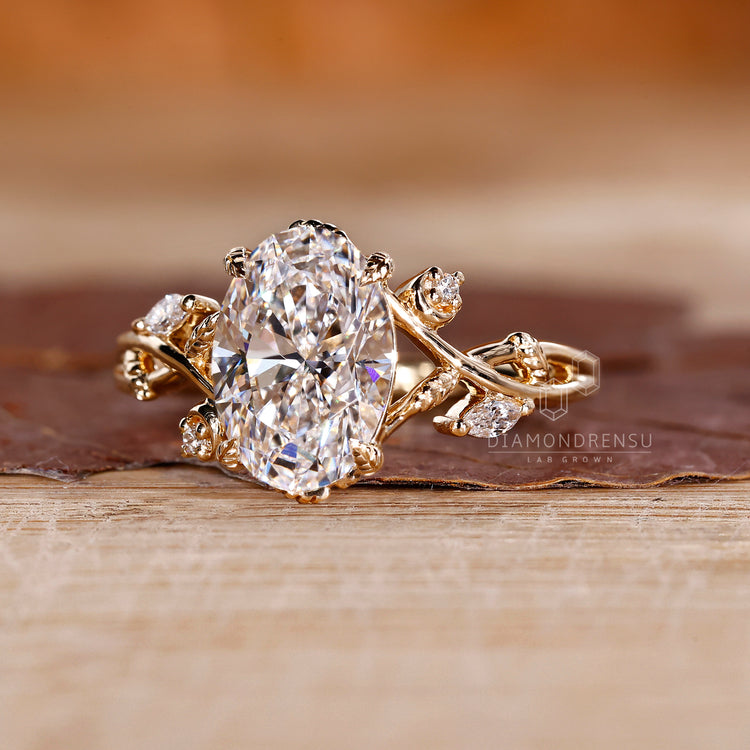 Oval diamond ring with leaf vine and side stones.