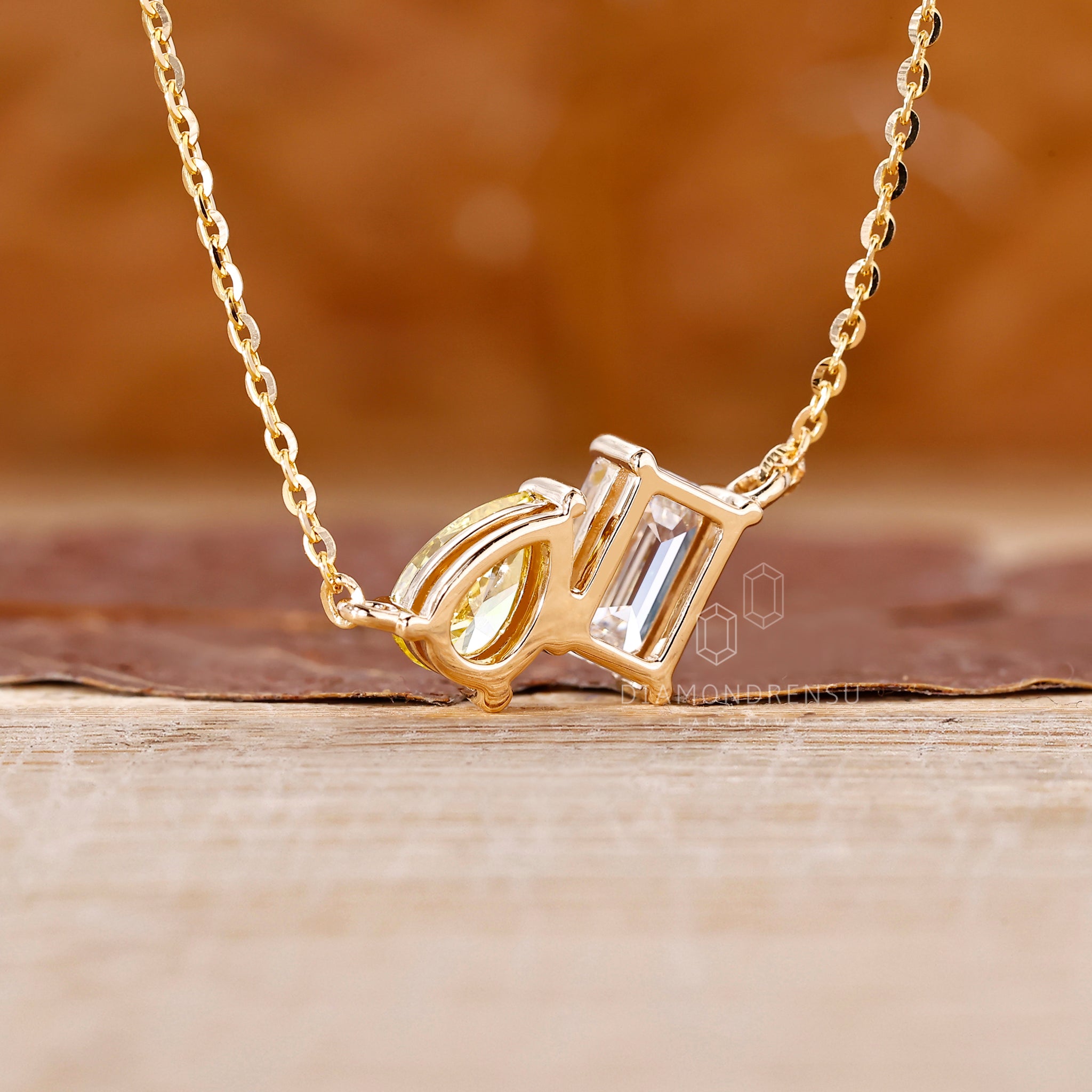 Shared prong pendant holding emerald and pear cut Lab Grown Diamonds.

