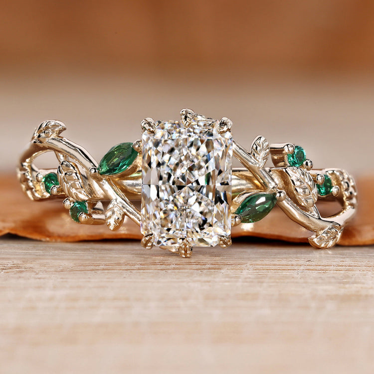 Radiant cut engagement ring with green emerald gemstones.