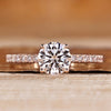 Round cut engagement ring with round pavé diamond details.