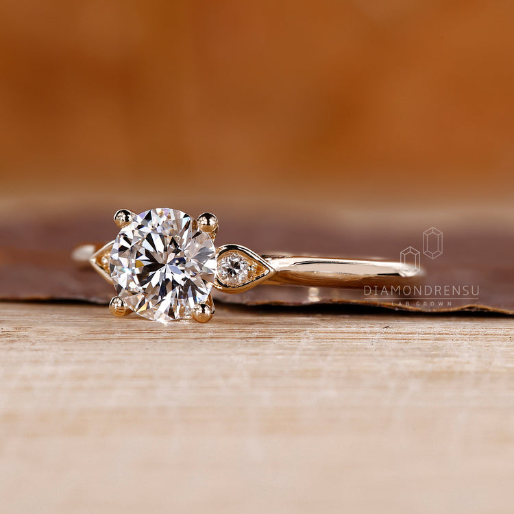 Round diamond ring with pear outline and side stones.