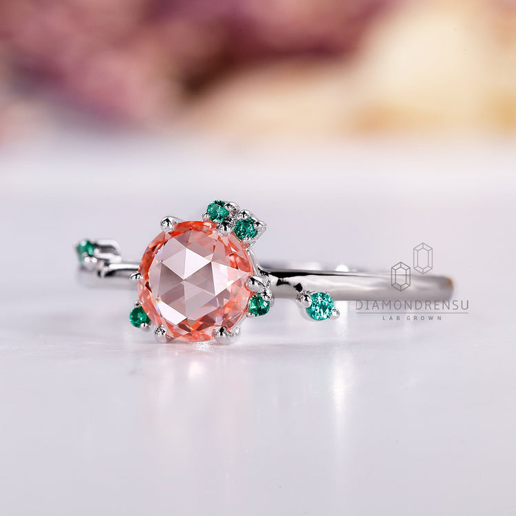 Peach sapphire ring with round cut and cluster setting.