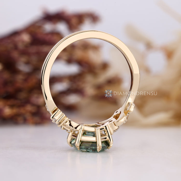 Round side stones with green hexagon cut diamond.