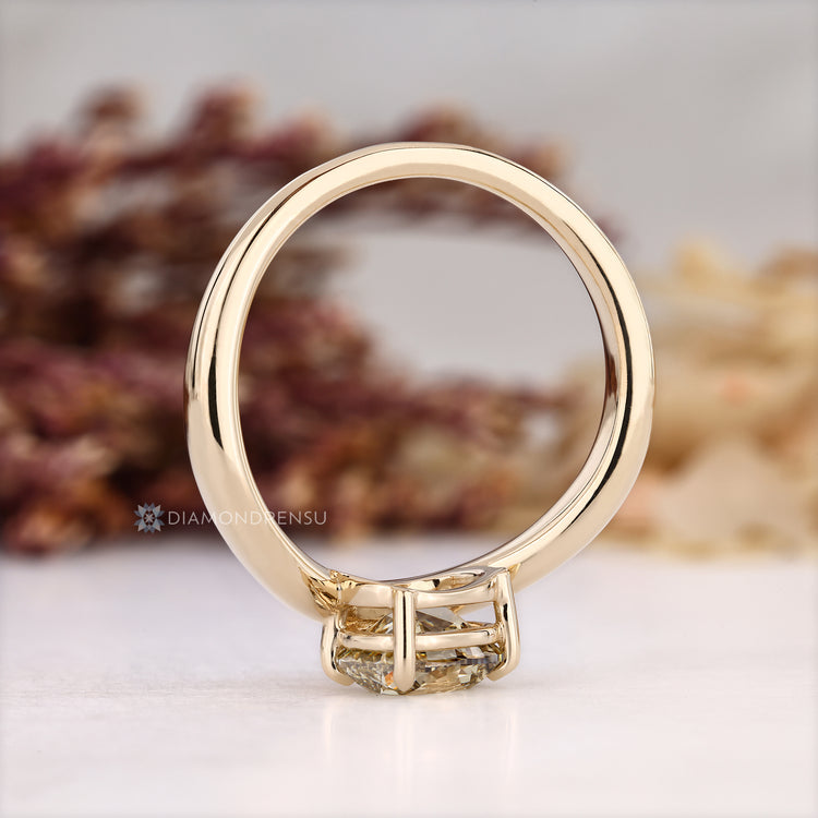 Lab grown yellow cushion diamond ring with four claw prongs.