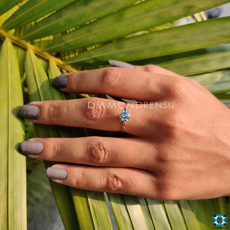 Custom engagement ring with a blue moissanite center.
