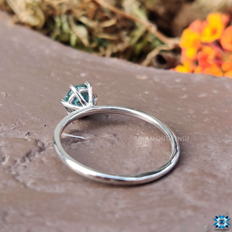 Custom white gold ring featuring round blue moissanite.
