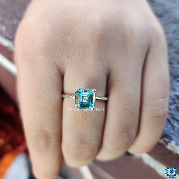 White gold solitaire ring with Asscher cut blue moissanite.
