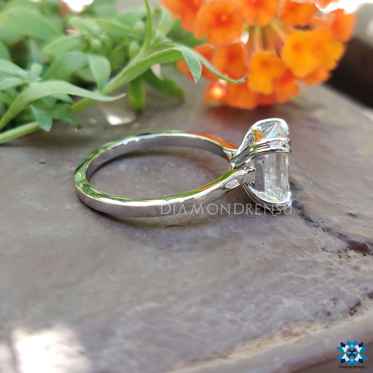 Cathedral setting engagement ring with emerald moissanite.
