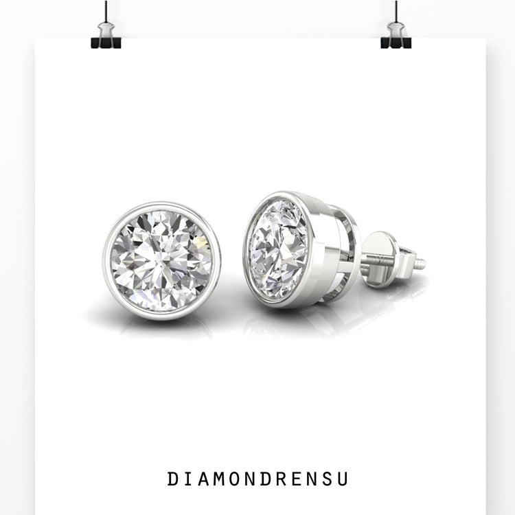 Elegant bezel set round diamond earrings in gold studs.
