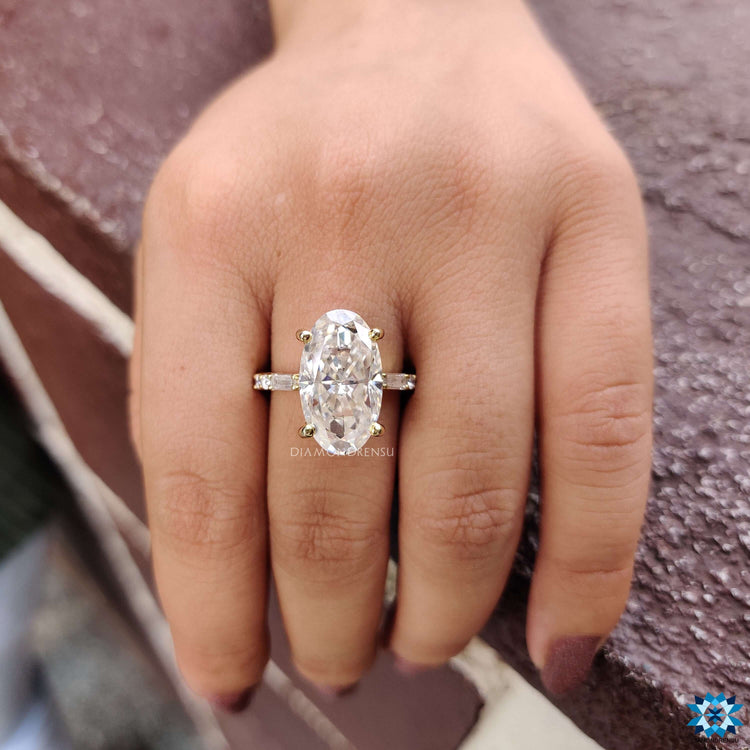 Yellow gold moissanite ring with prong setting and baguette accents.
