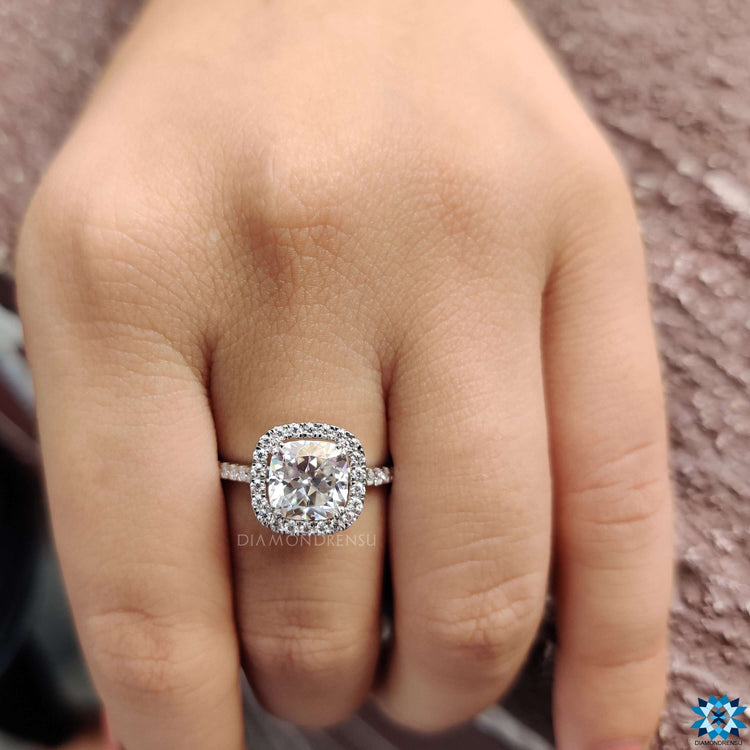 Cushion Rensu cut moissanite halo ring with a round pave band.
